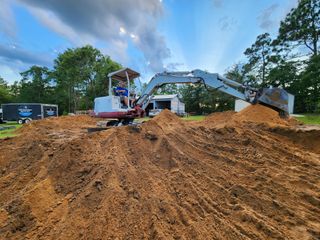 A man is driving an excavator through a pile of dirt.