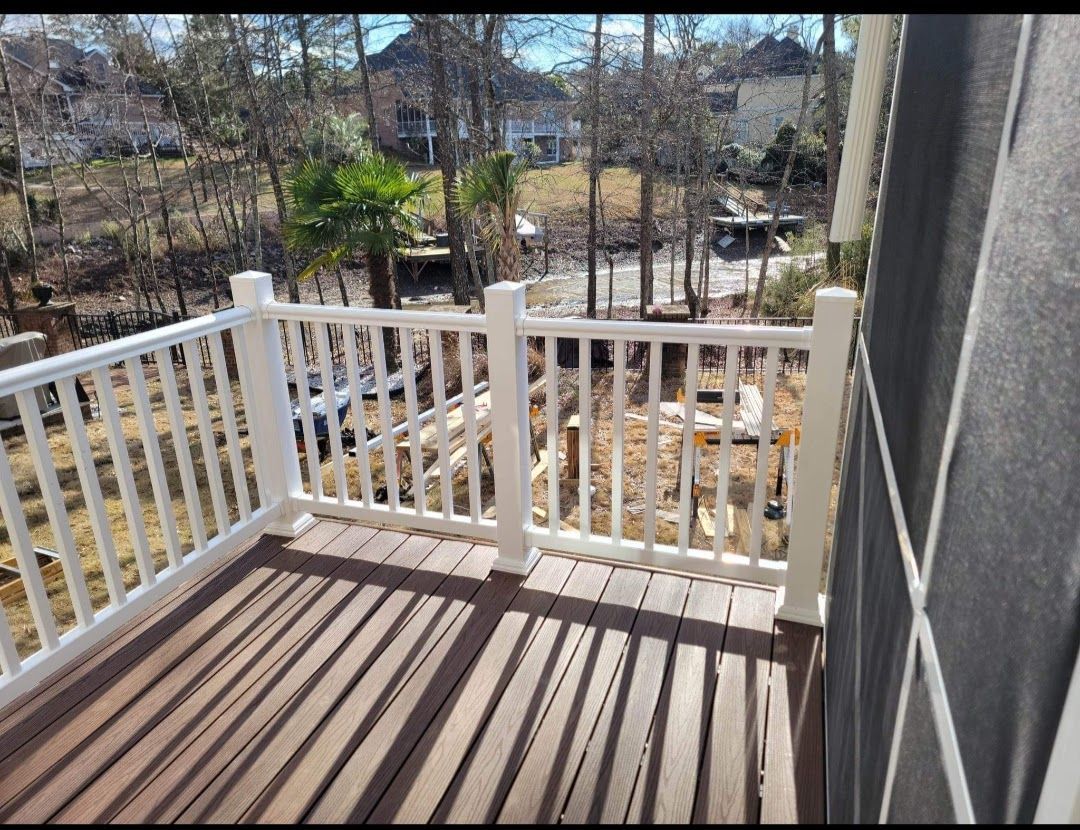 A balcony with a white railing and a view of a forest.