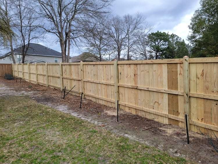 A wooden fence is being built in the backyard of a house.