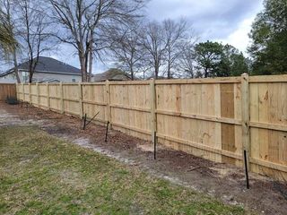A wooden fence is being built in the backyard of a house.