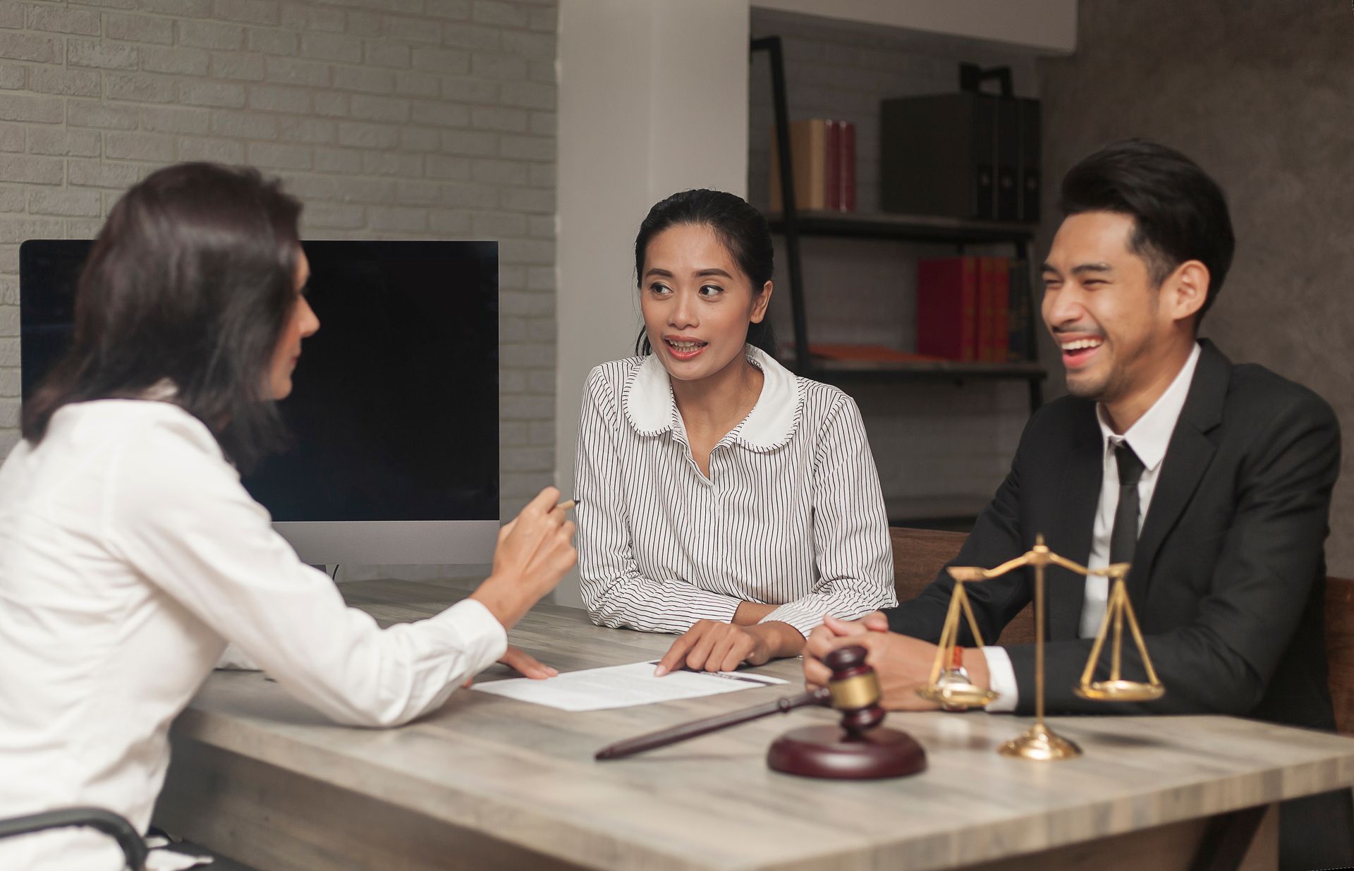 Lawyer advising a couple at a table; Scales of justice and gavel are present.
