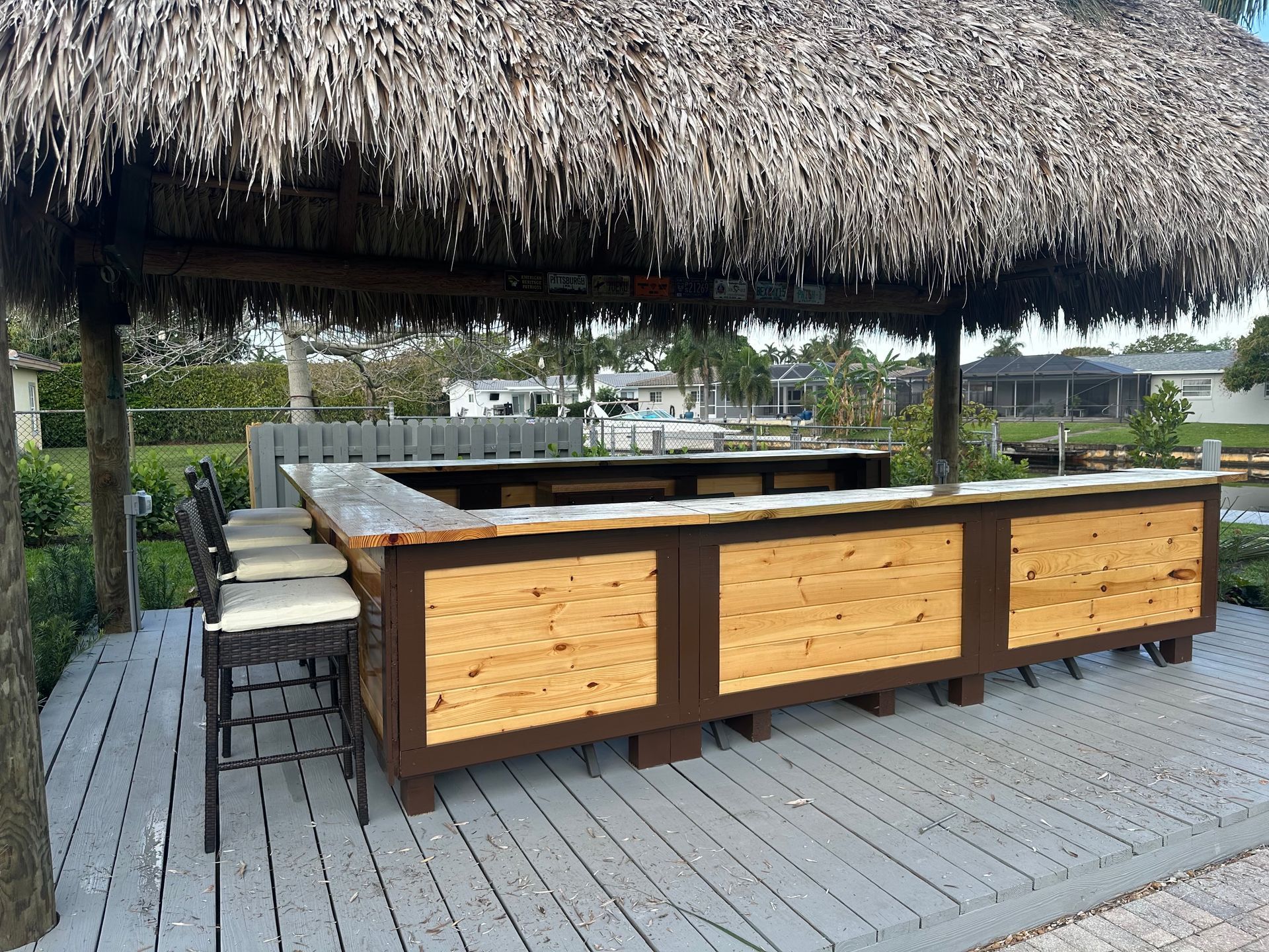 Thatched outdoor bar on a wooden deck with stools and marina view