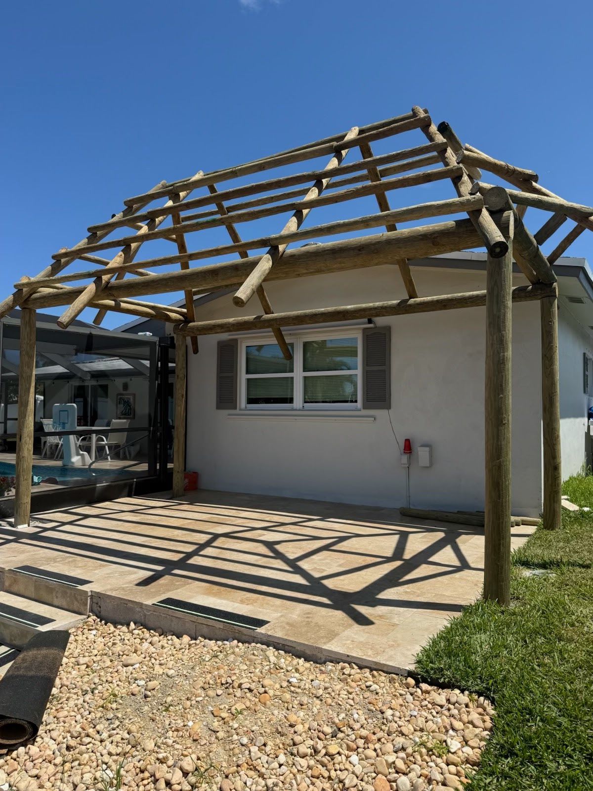 House under renovation with exposed roof framing over a front porch and concrete patio