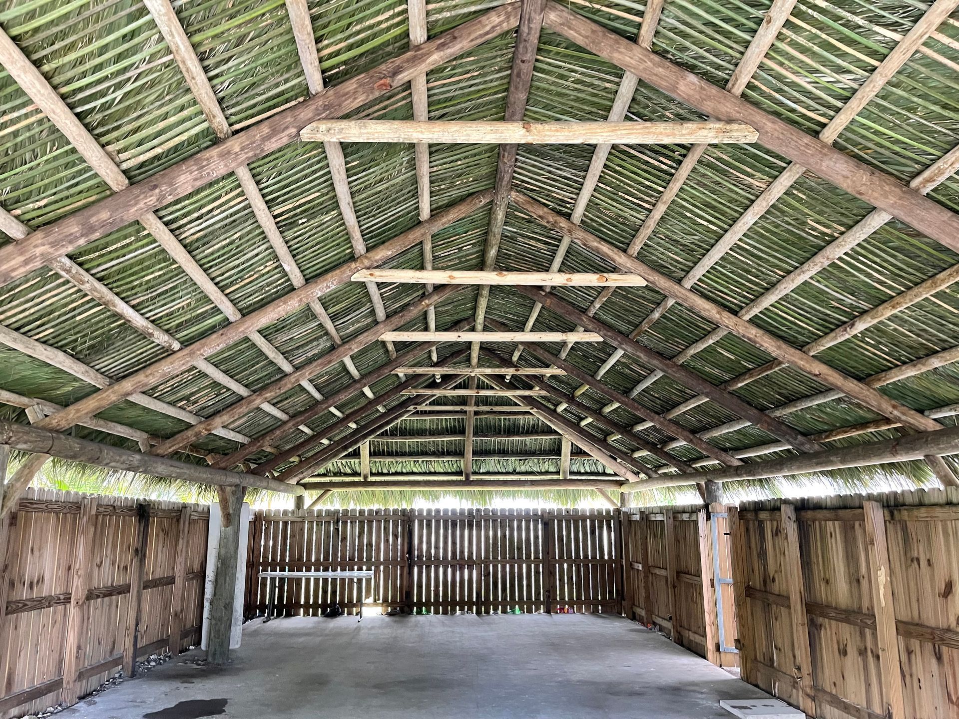 Open-air wooden pavilion with a thatched roof and bamboo walls, viewed from the center.