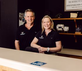 A man and a woman are standing behind a counter and smiling