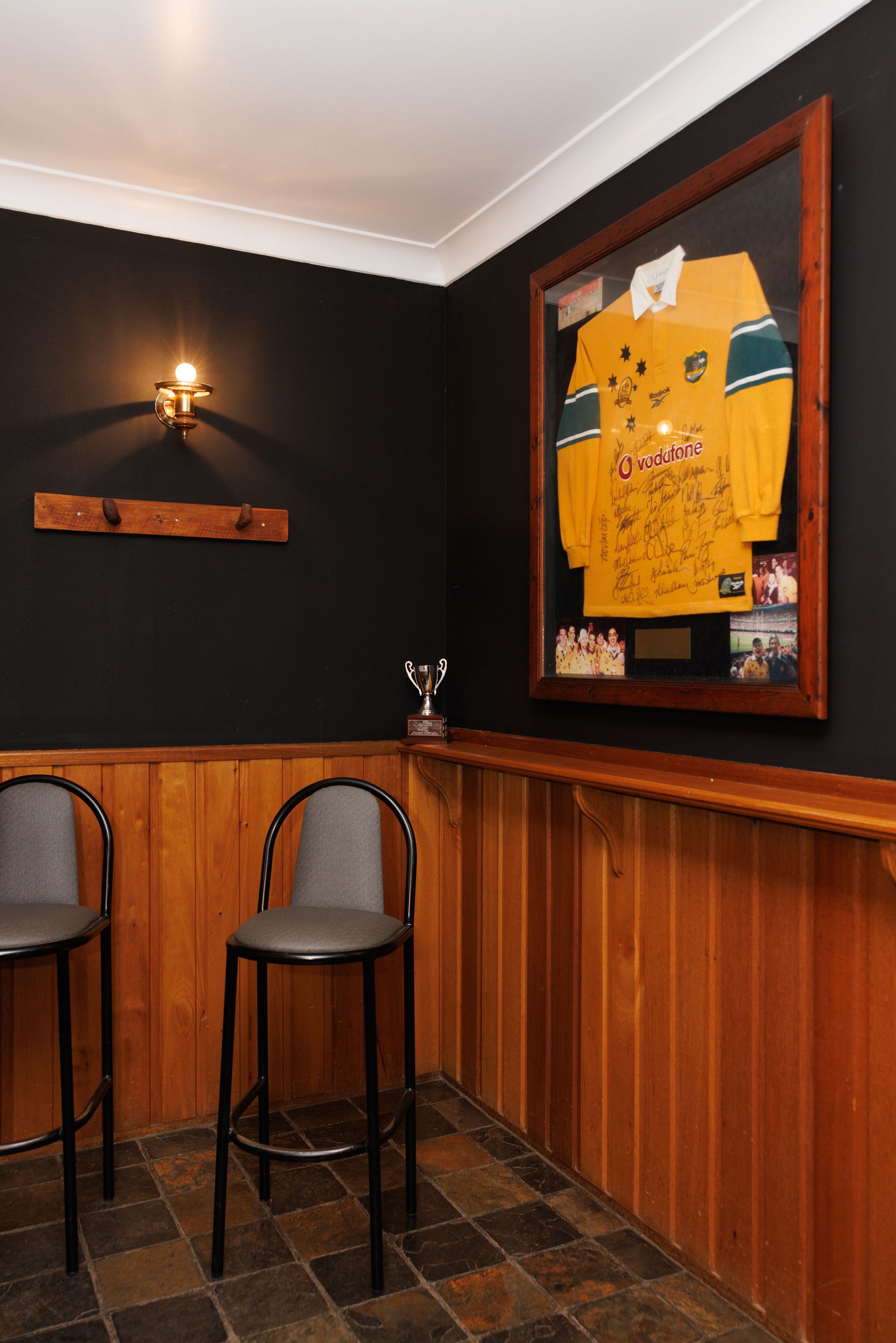 A corner of a room with two stools and a framed jersey on the wall