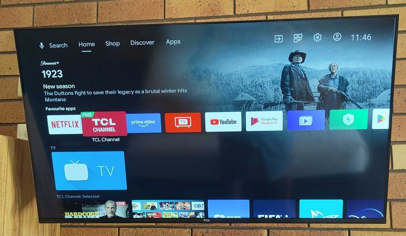 A tcl tv is hanging on a brick wall