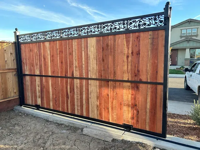 Wooden fence gate with decorative metal top and frame.