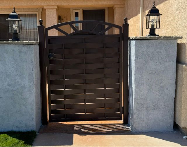 Brown wooden gate between stucco walls with black lanterns at a house entrance