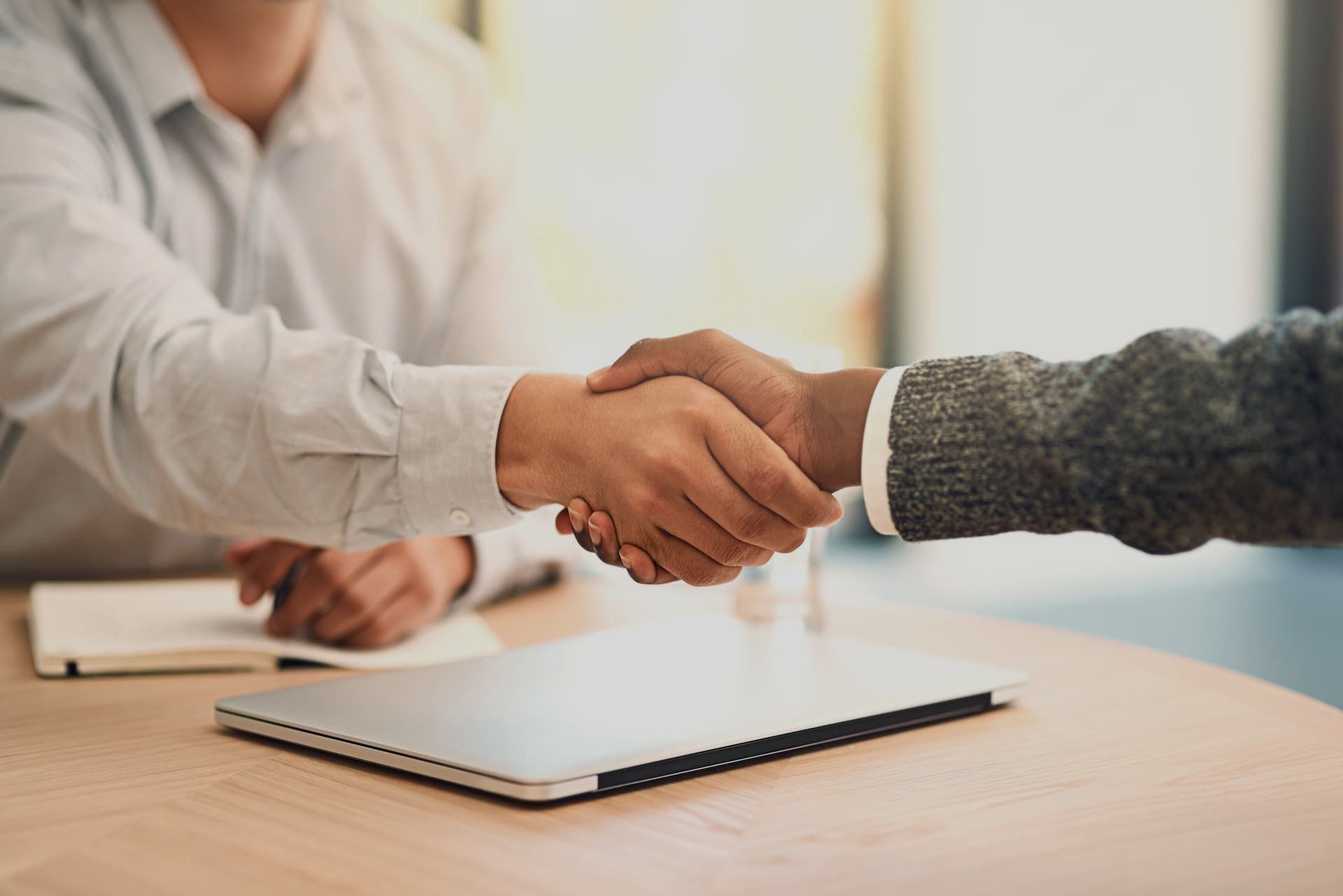 A man and a woman are shaking hands at a table.
