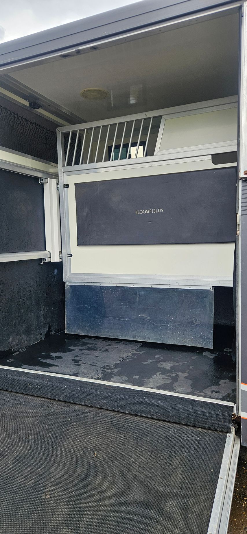 Interior of a vehicle with a wheelchair lift/ramp and folding bench seats in gray and white.