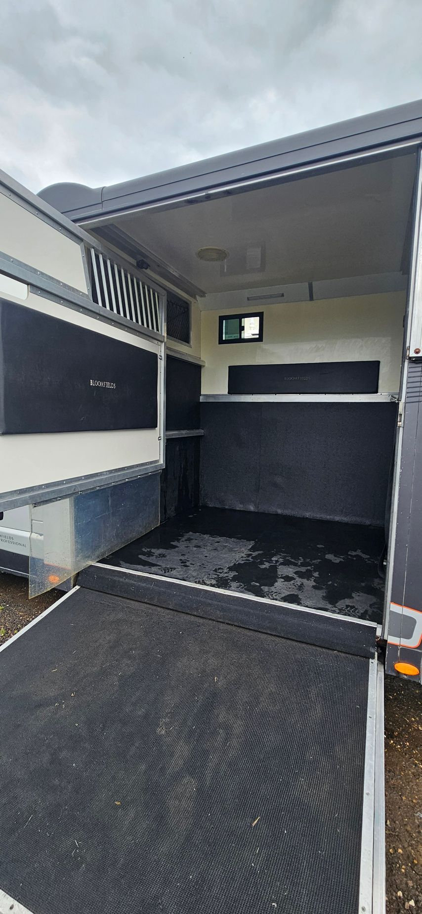 Open cargo trailer with black interior and ramp door, viewed from the rear.