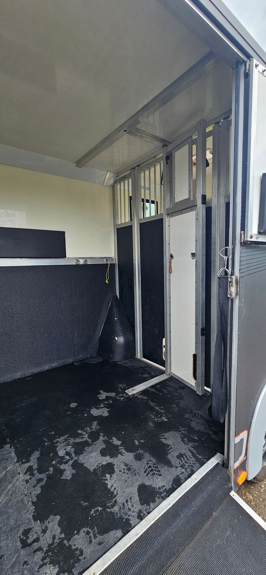 Open cargo trailer interior with black floor and fold-down ramp at the back.