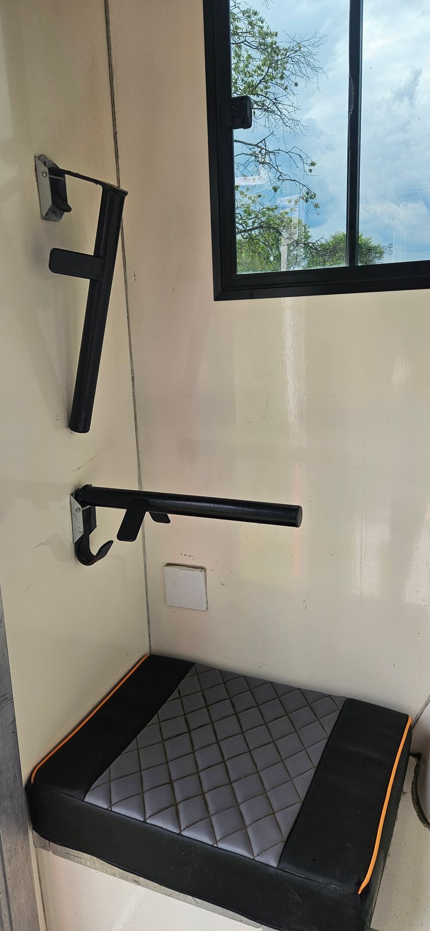 Accessible shower with wall-mounted grab bars, fold-down seat, and tiled floor by a window