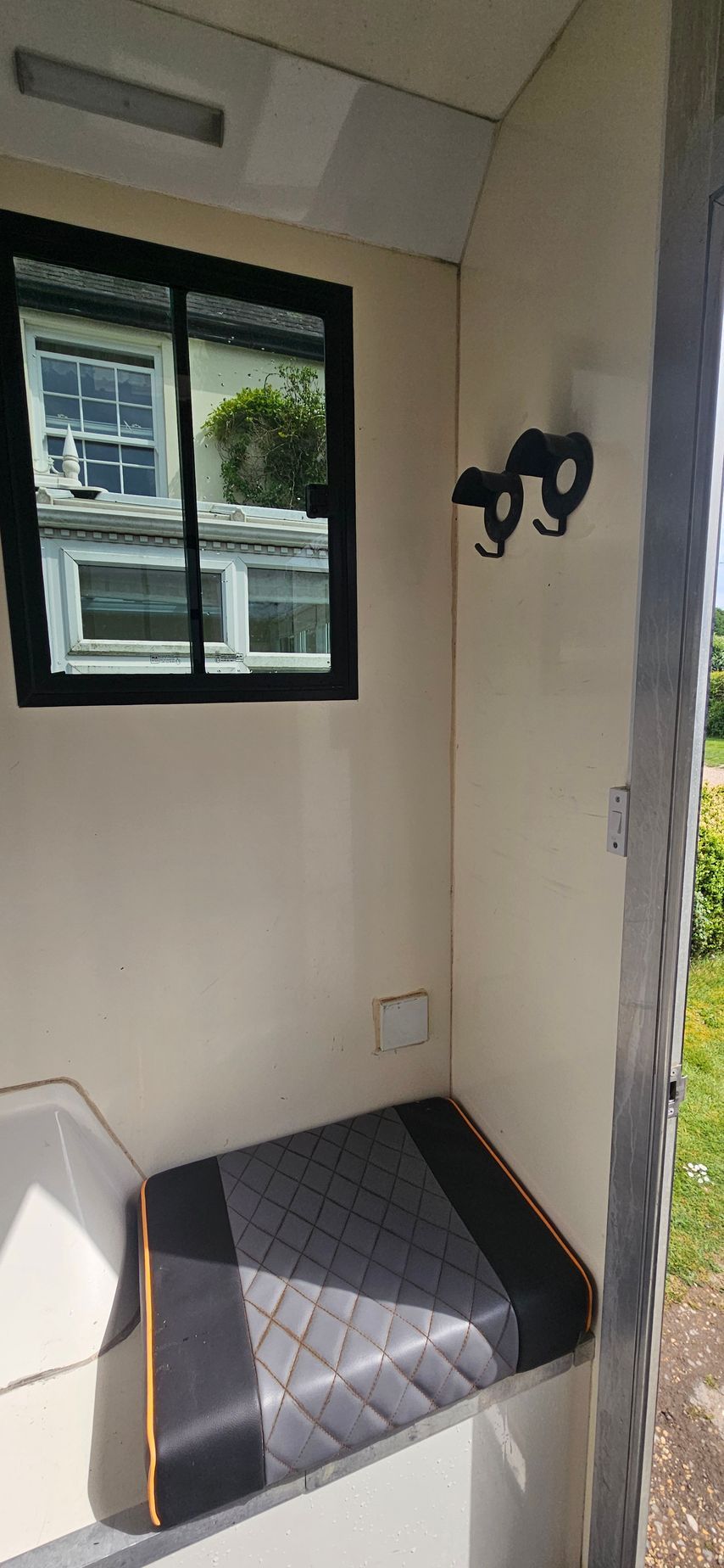 Small entry nook with a cushioned bench, window, wall hooks, and light-colored walls.