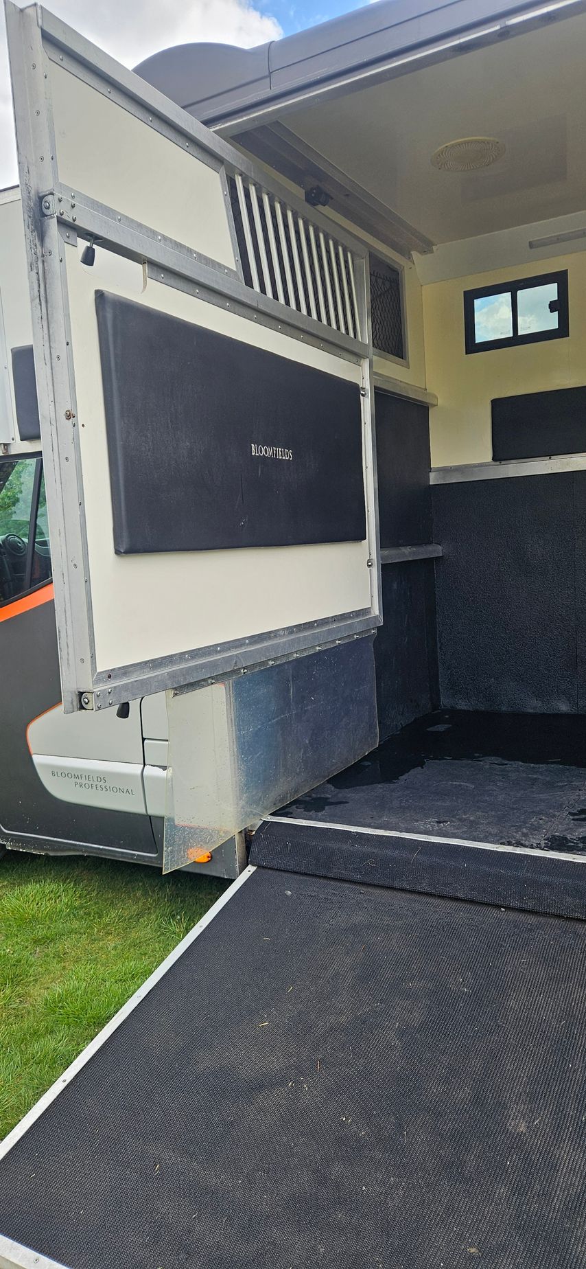 Open RV side entrance with ramp and interior steps visible, black and white exterior