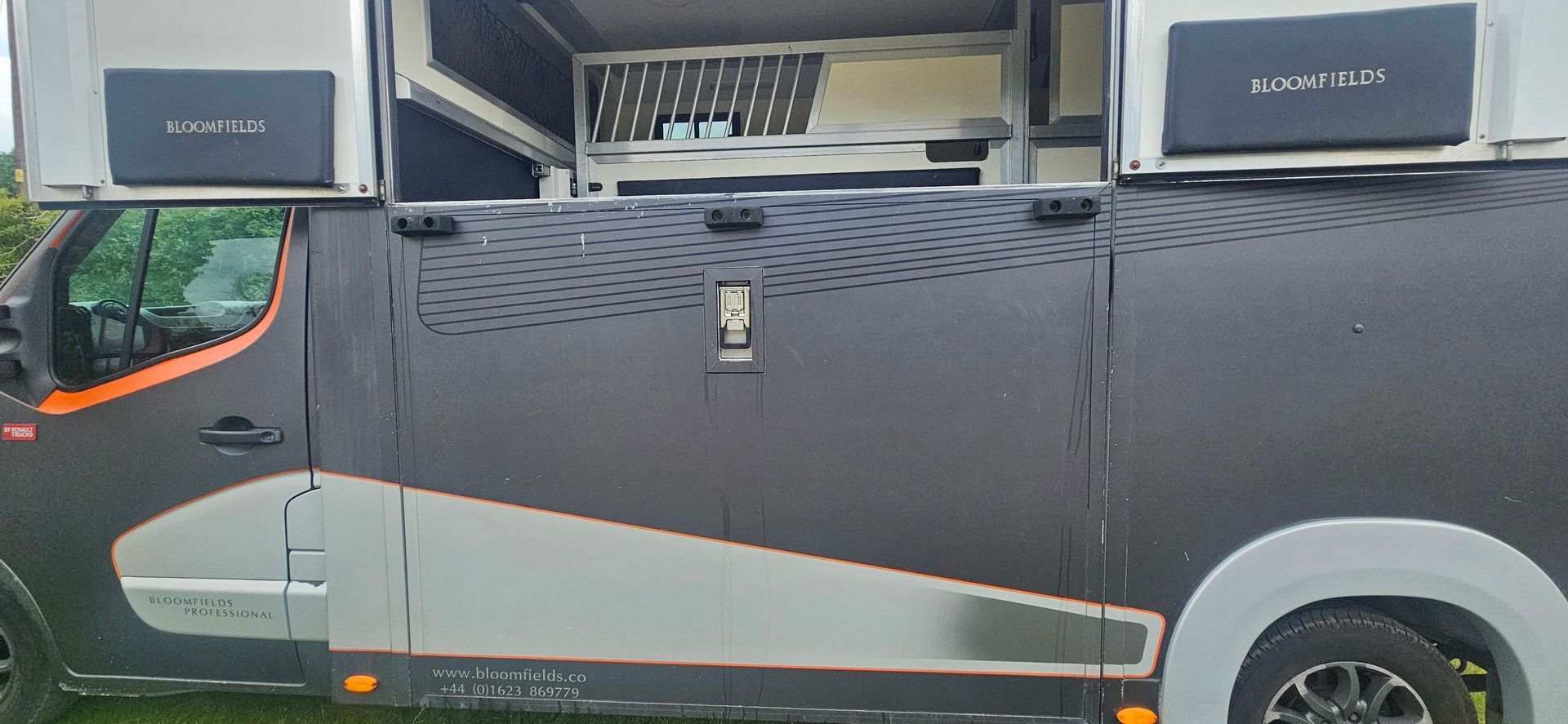 Black utility truck with rooftop speakers and silver side panel parked outdoors