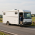White delivery truck parked roadside with a person standing by the driver’s door in a rural area