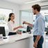 Receptionist handing keys to a customer at a bright car dealership counter