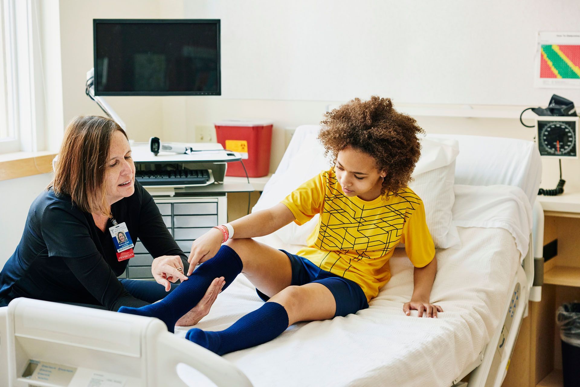 A healthcare worker examines a child's leg on a hospital bed