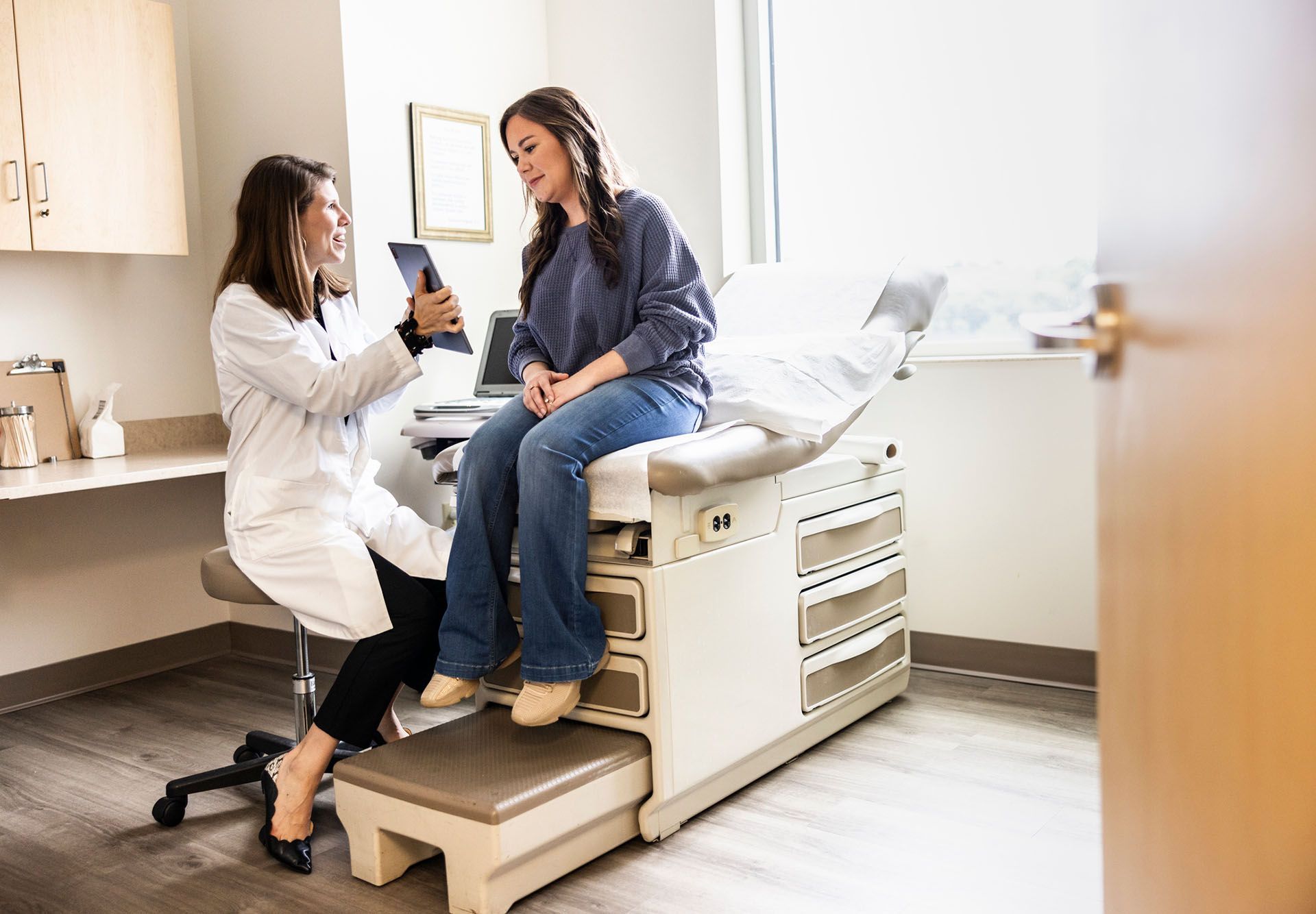 A doctor showing a tablet to a patient in an exam room