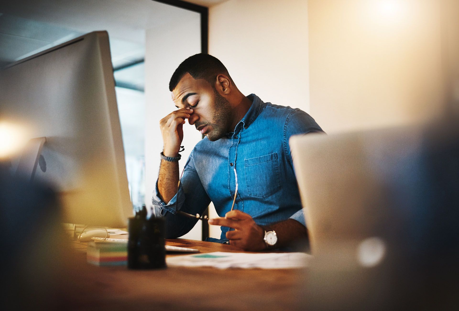 A stressed man at the desk is holding his face