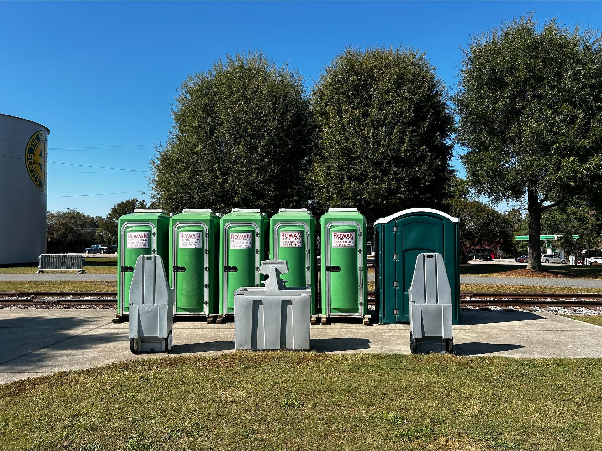 Two portable toilets are sitting next to each other in a grassy field.
