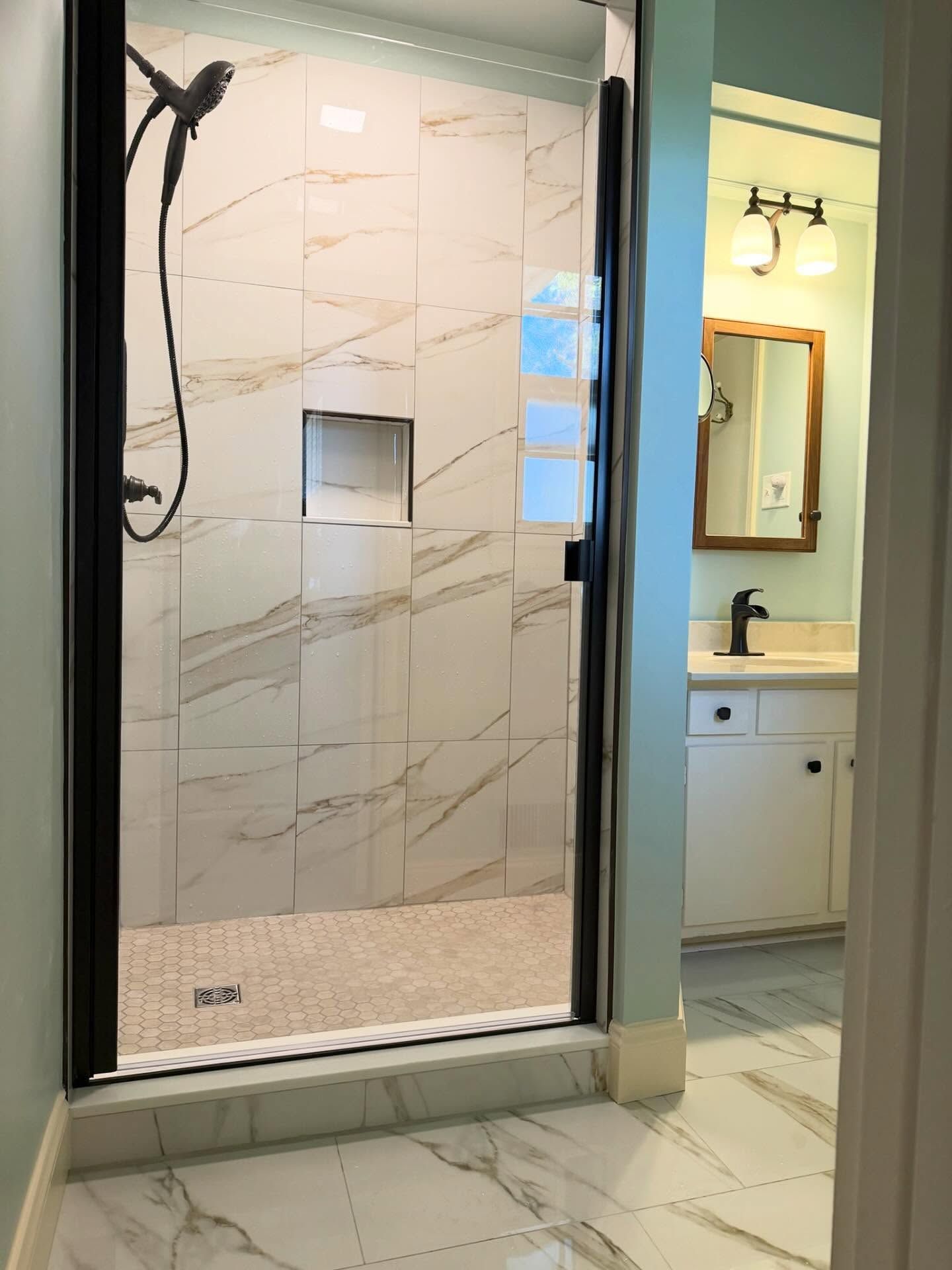 Bathroom with walk-in shower, glass door, tiled walls, and a sink area visible beside it Bathroom with walk-in shower, glass door, tiled walls, and a sink area visible beside it