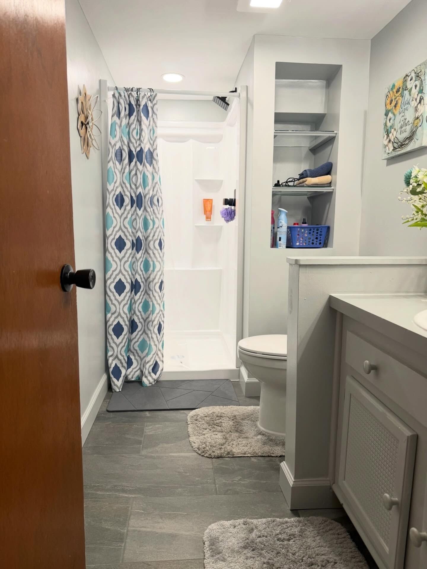 Small bathroom with shower curtain, toilet, gray rug, and white vanity cabinets. Small bathroom with shower curtain, toilet, gray rug, and white vanity cabinets.