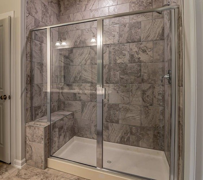 Modern glass-enclosed shower with gray tile walls and built-in bench in a bathroom Modern glass-enclosed shower with gray tile walls and built-in bench in a bathroom
