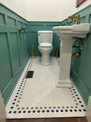 Small teal bathroom with toilet, pedestal sink, and white hex tile floor.