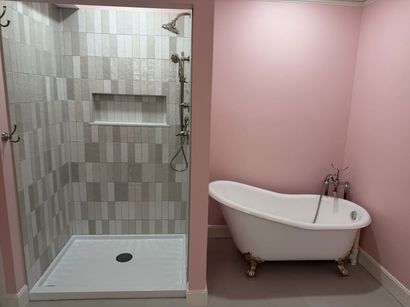 Pink bathroom with a walk-in shower and a white clawfoot bathtub