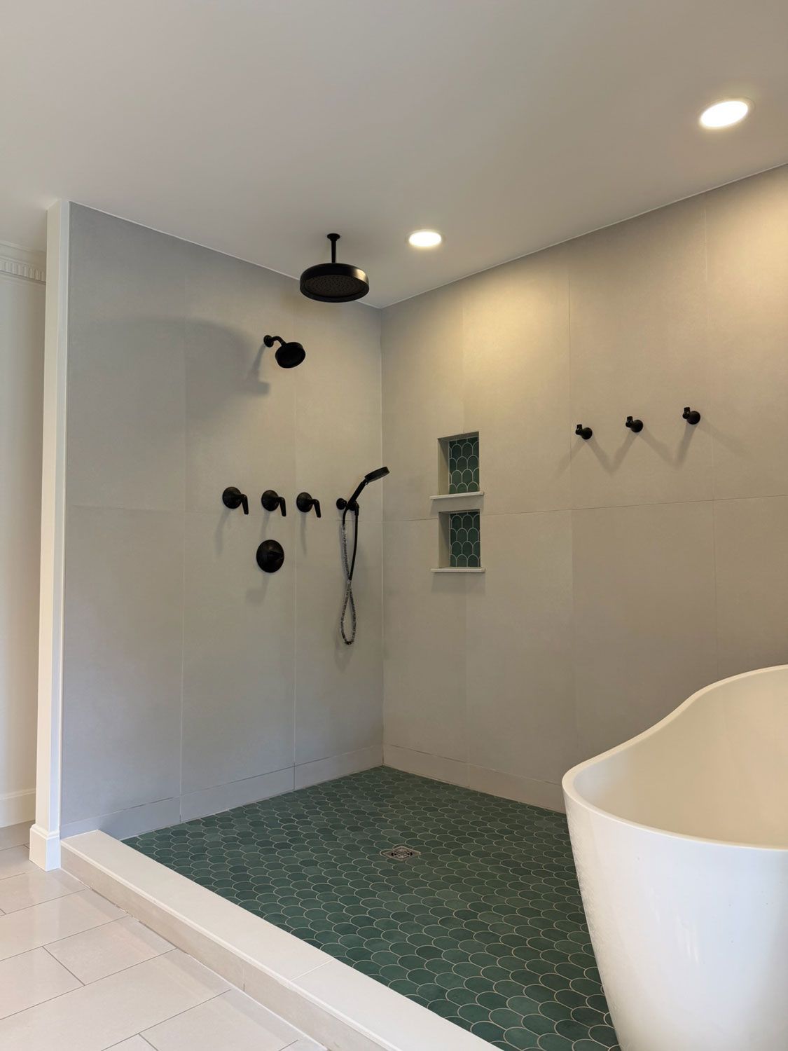 Modern bathroom with green-tiled walk-in shower, black fixtures, white walls, and soaking tub edge Modern bathroom with green-tiled walk-in shower, black fixtures, white walls, and soaking tub edge