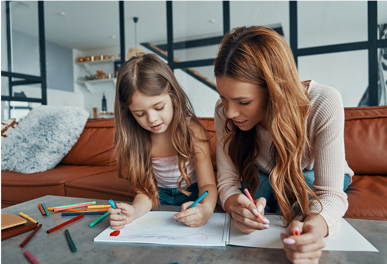 Woman and child draw together at a table, colored pencils visible.