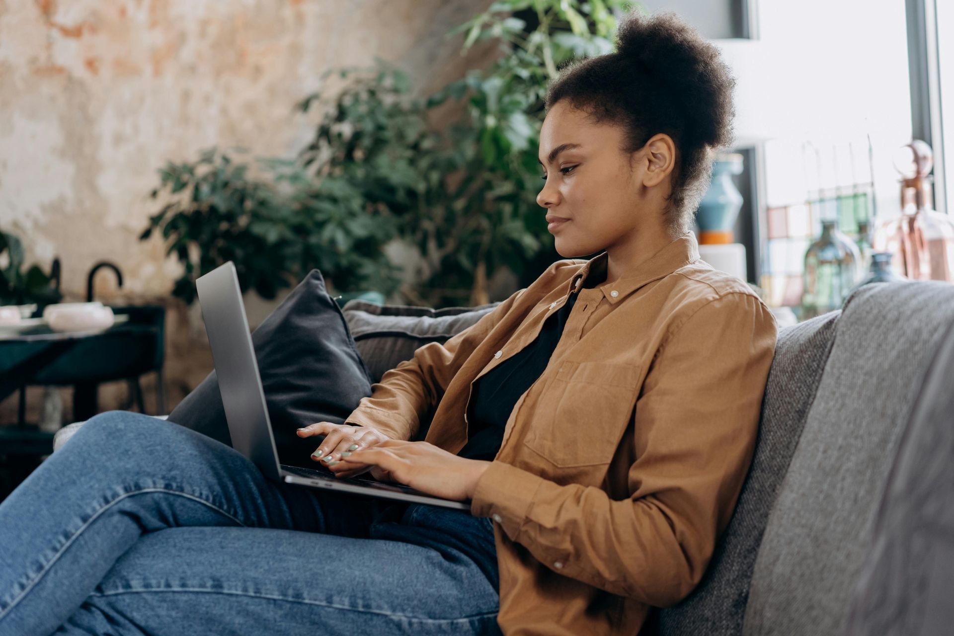 Woman sitting on a couch working on a laptop, indoors.