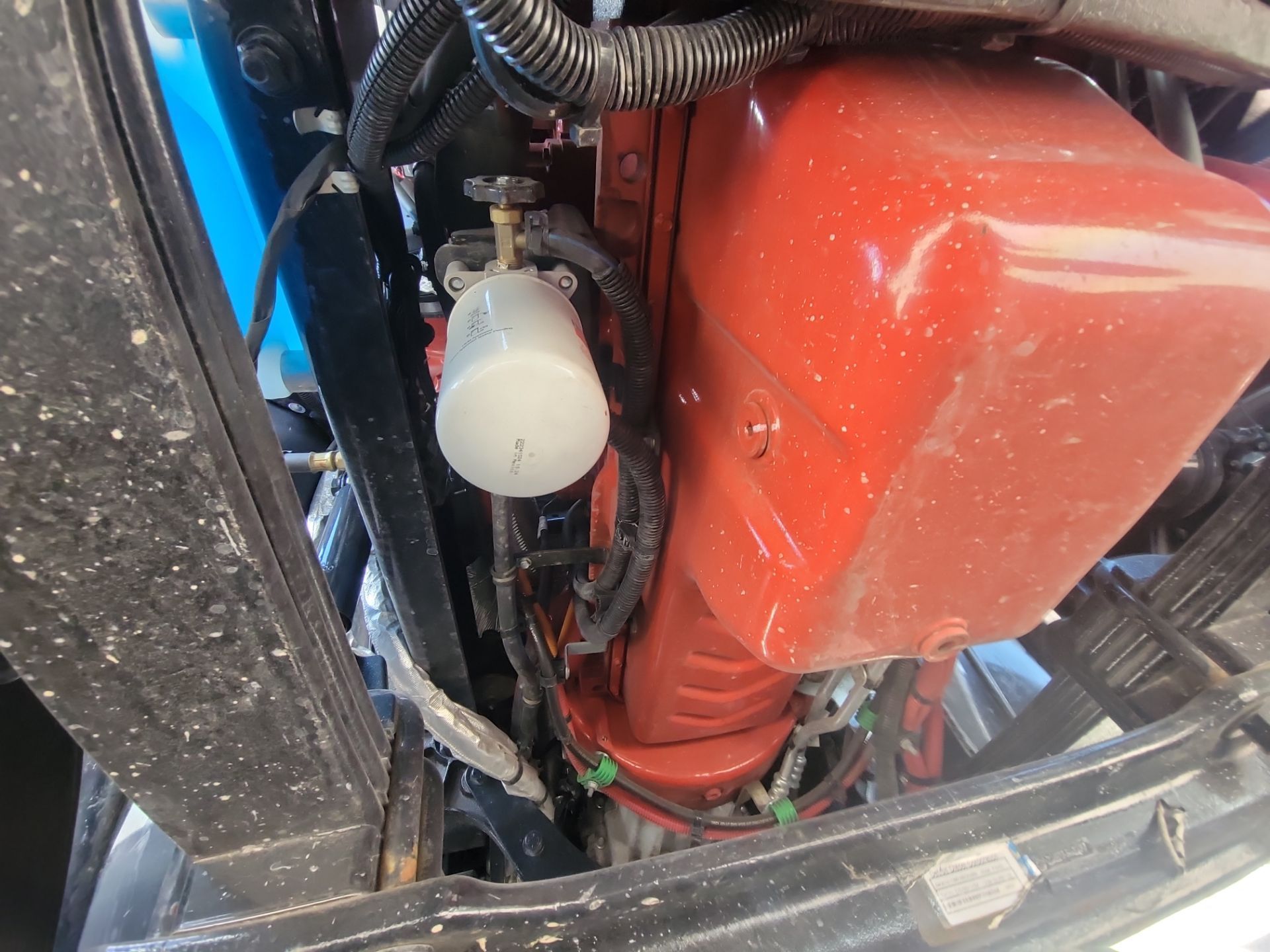 A close up of a red engine with a fuel filter attached to it.