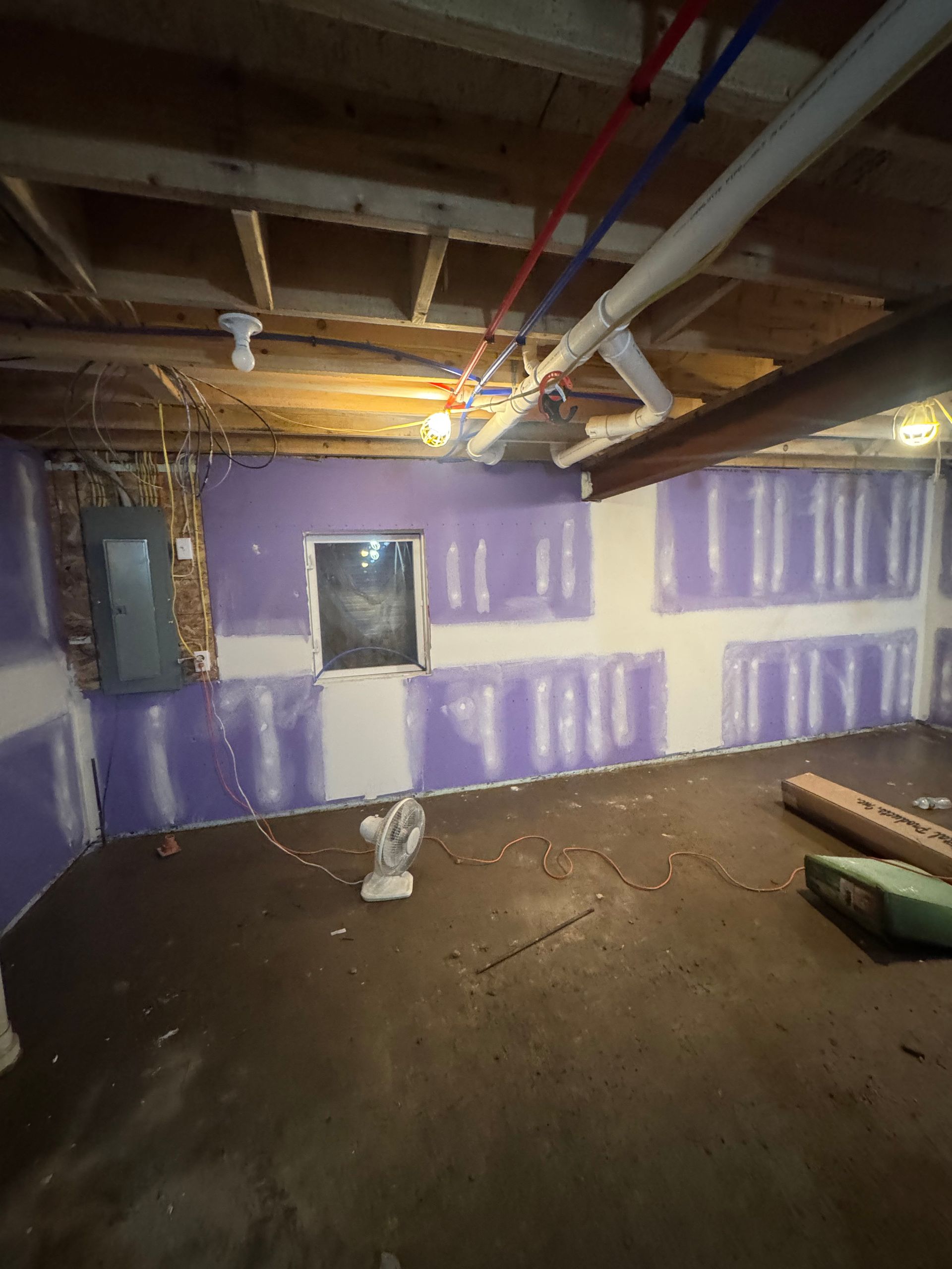 Renovation room with unfinished walls, ladder, worktable, and large window with blinds