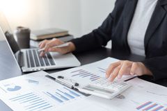 Person working on a laptop beside printed financial charts and reports at a desk