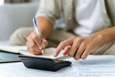 Hands using a calculator and pen over paperwork at a desk