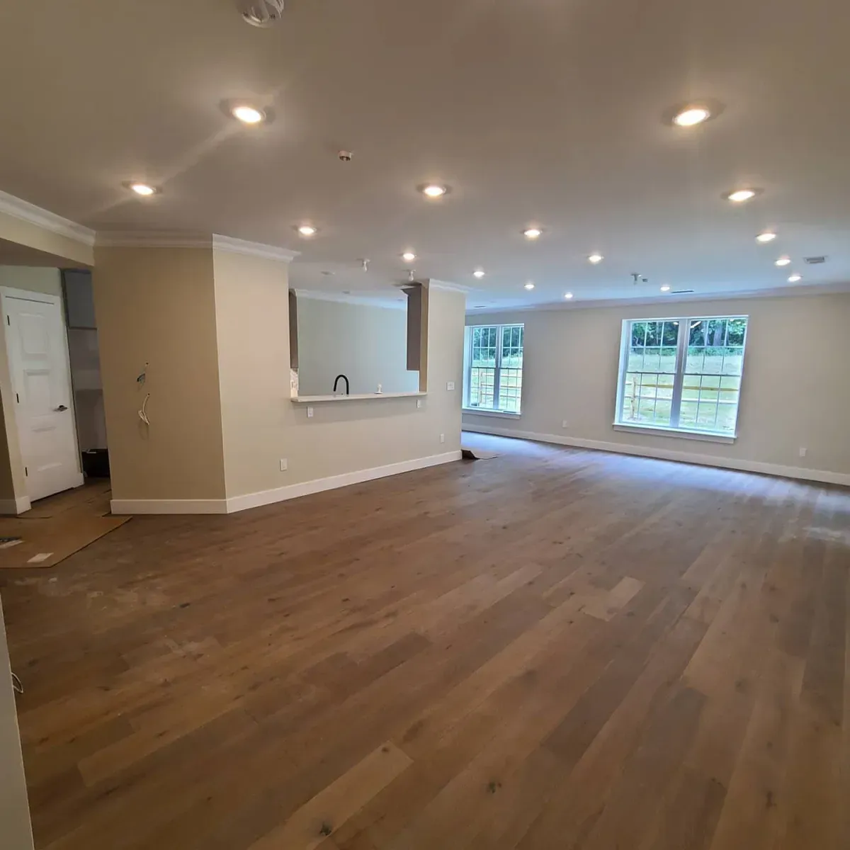 A large empty living room with hardwood floors and lots of windows.