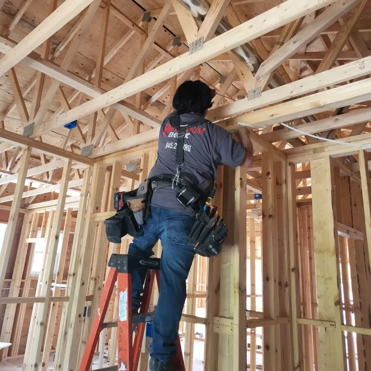 A man is standing on a ladder in a house under construction