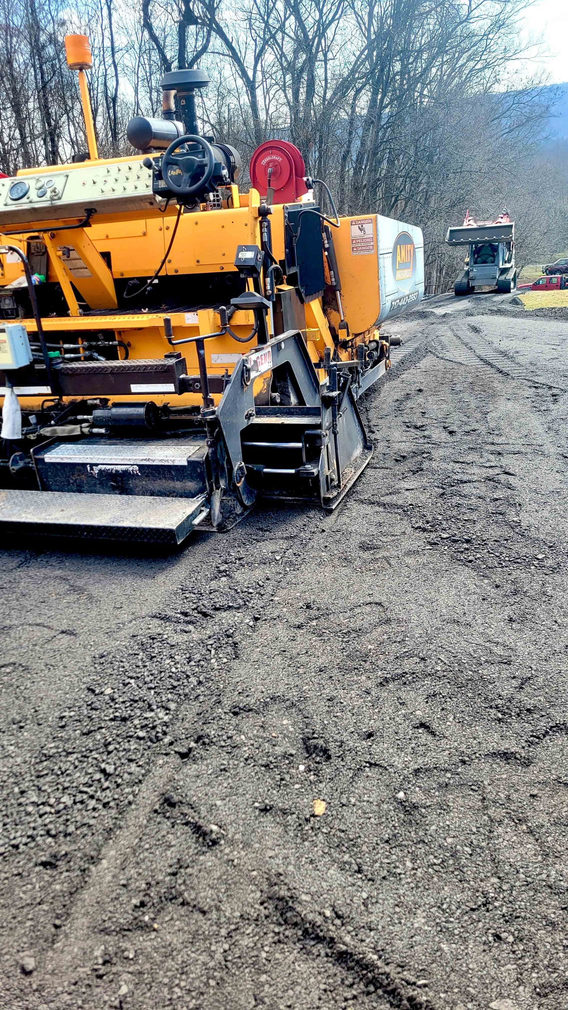 A machine is laying gravel on a road.