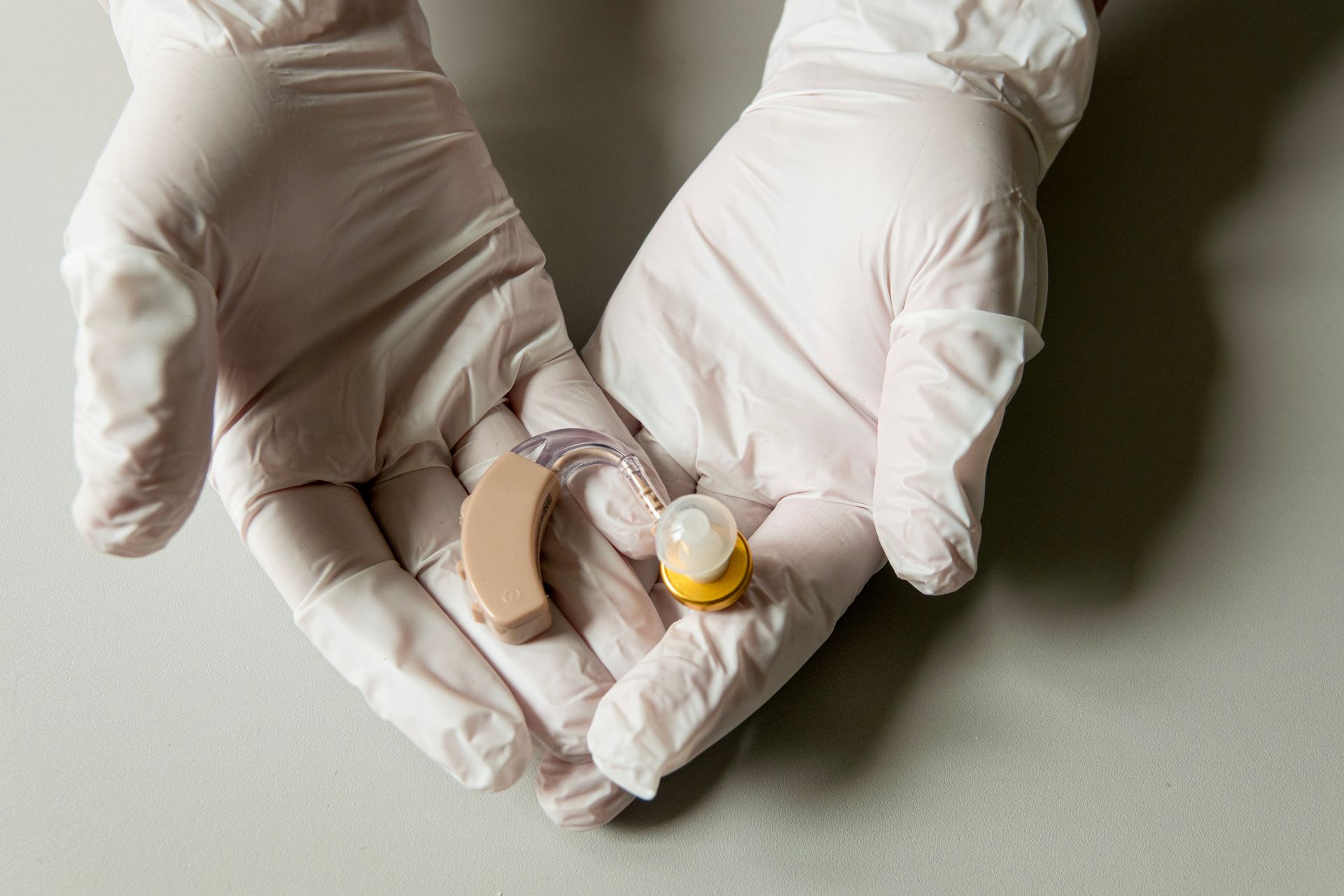 Close-up of a worker's hands in gloves after performing a hearing aid repair service.