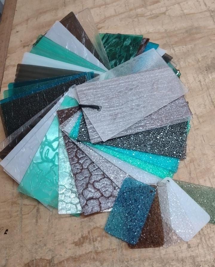 Abanico de muestras de tela variadas, brillantes y estampadas, dispuestas sobre una mesa.
