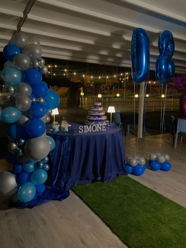 Un tavolo decorato con palloncini blu e argento e una torta.