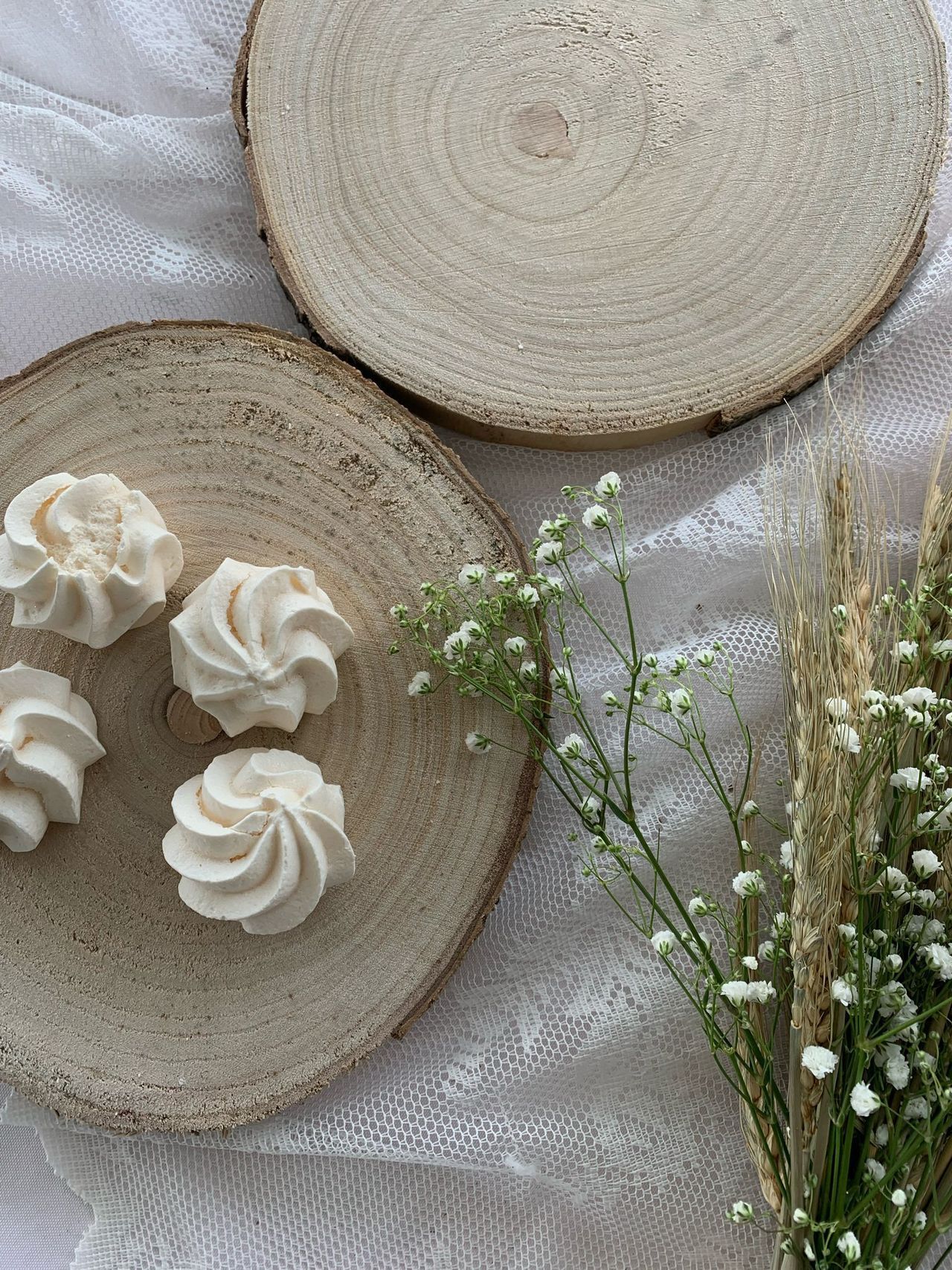 Due piatti di legno ricoperti di glassa bianca sono seduti su un tavolo accanto ai fiori.