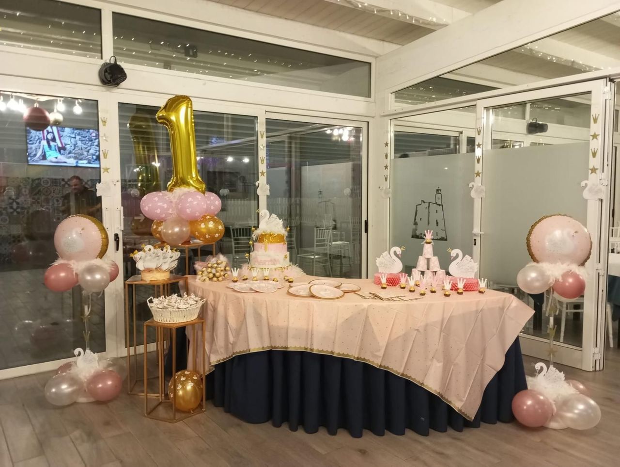 Un tavolo addobbato con palloncini e una torta per il primo compleanno.