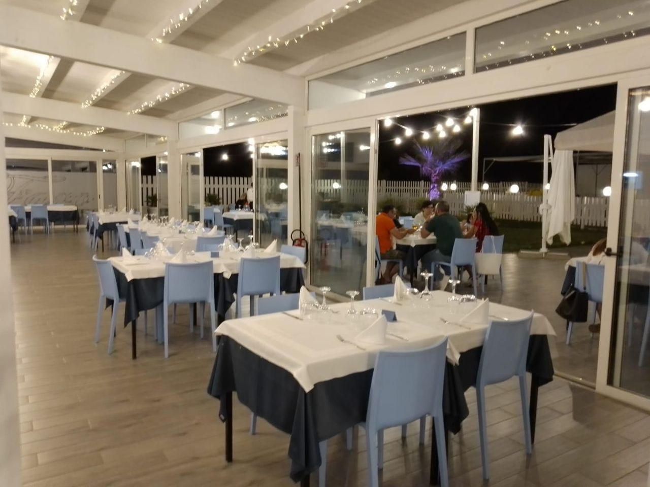 Un ristorante con sedie blu e tavoli bianchi