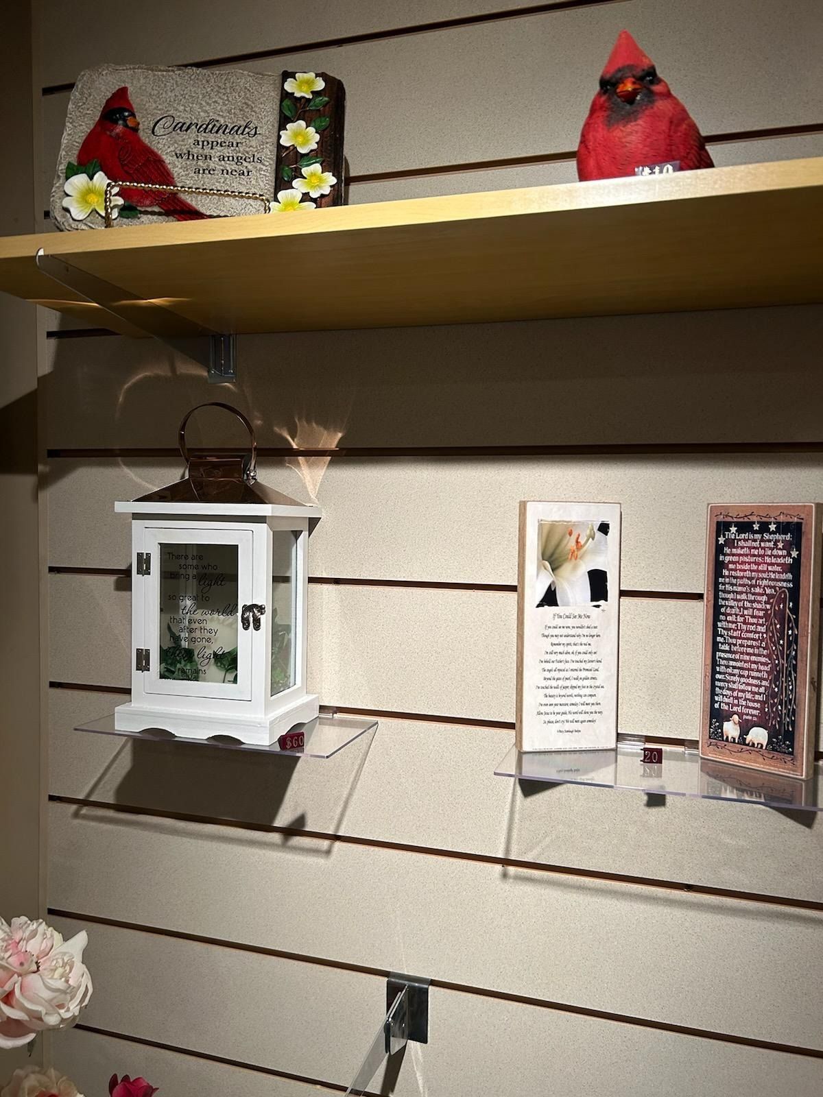 Shelved display of decorative lanterns and handmade signs on a slatwall in a shop or gallery