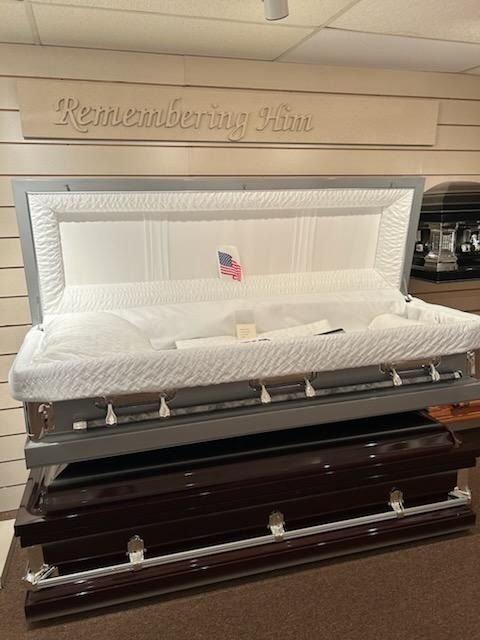 Open casket with white interior and silver lining in a funeral home display room